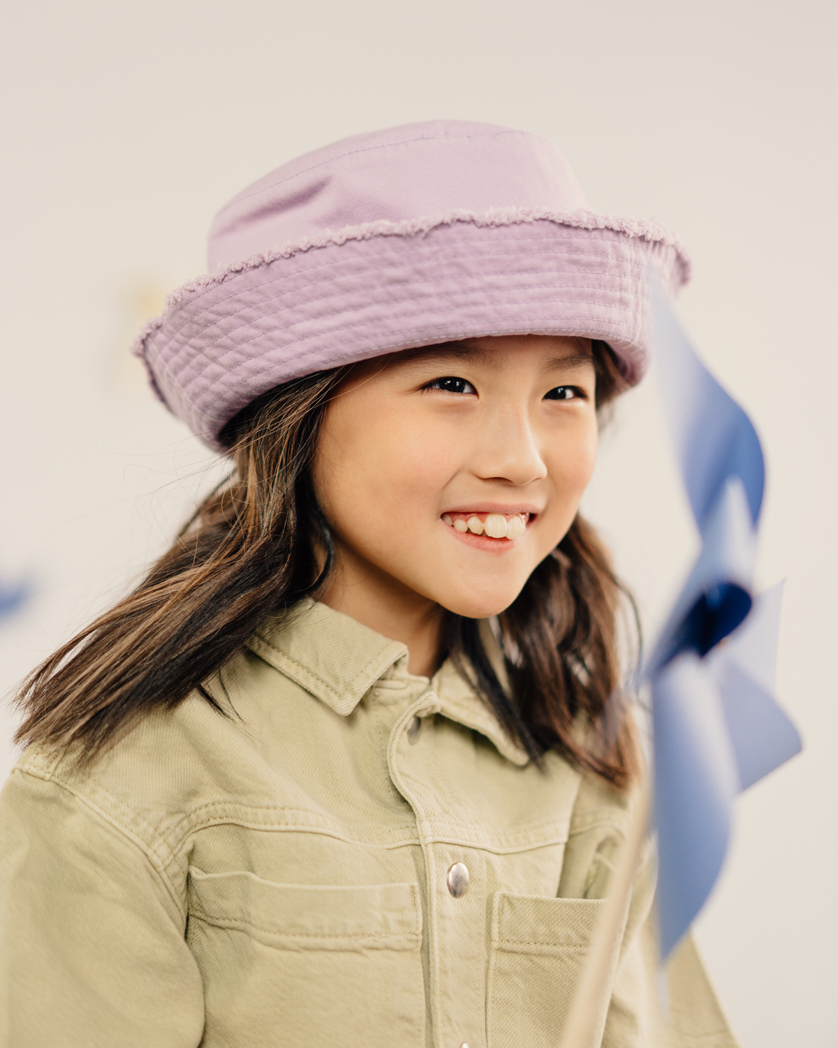 A Girl in Beige Shirt Smiling while Wearing a Purple Hat